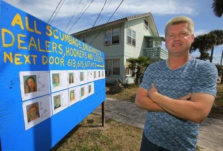 Mike Manderville stands in front of a sign of mug shots of his neighbors on Braddock Avenue in Daytona Beach. News-Journal/NIGEL COOK