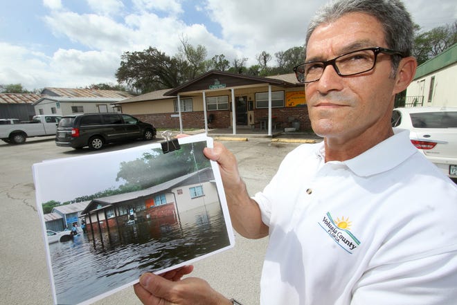 John Angiulli, Volusia County's public works director, holds a photograph showing how the county's maintenance facility in Holly Hill can flood while standing before the building. The county is hoping to build a central facility to replace aging and far-flung facilities. News-Journal/David Tucker