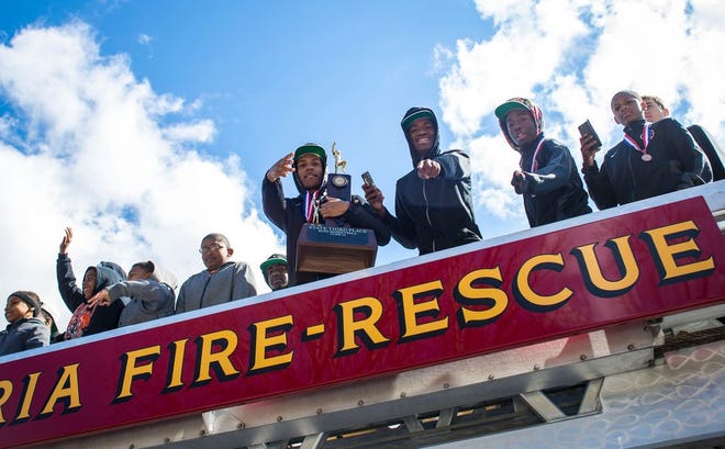 Manual basketball players and ball boys wave and pose for photos from atop a fire truck while on the parade route to Manual Academy in Peoria on Sunday. The varsity boys basketball team took third place in state over the weekend, prompting school officials and community members to hold a parade through town and a ceremony at the school.