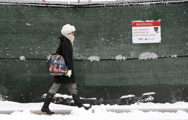 A woman walks past a construction site as snow falls in the East Boston neighborhood of Boston, Monday, March 21, 2016. The National Weather Service says southeastern Massachusetts, including Boston and Rhode Island could get several inches of snow through Monday morning. (AP Photo/Michael Dwyer)