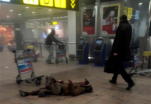 In this photo provided by Georgian Public Broadcaster and photographed by Ketevan Kardava, an injured man lies on the floor in Brussels Airport in Brussels, Belgium, after explosions were heard Tuesday, March 22, 2016. A developing situation left a number dead in explosions that ripped through the departure hall at Brussels airport Tuesday, police said. All flights were canceled, arriving planes were being diverted and Belgium's terror alert level was raised to maximum, officials said.