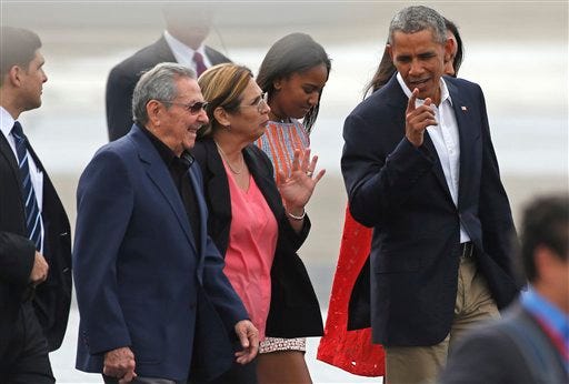 President Barack Obama, right, talks to Cuba's President Raul Castro, left, before boarding Air Force One on his way to Argentina, in Havana on Tuesday. Behind are Obama's daughters Sasha, second from right, and Malia, partially covered. Obama's visit was a crowning moment in his and Castro's bold bid to restore ties after a half-century diplomatic freeze. DESMOND BOYLAN/THE ASSOCIATED PRESS