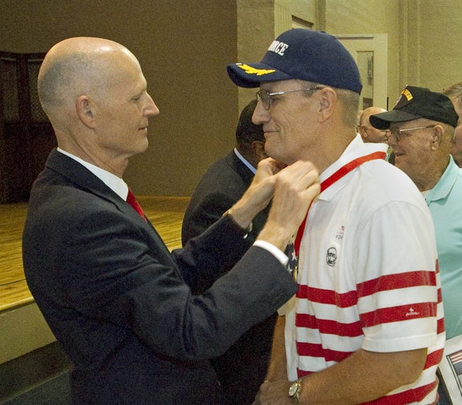 Gov. Rick Scott, left, presents U.S. Air Force Vietnam-era veteran Dave Madera, 66, of Auburndale, with the Governor's Veterans Service Award during a ceremony Tuesday afternoon at the Florida Army National Guard Armory in Winter Haven. A total of 192 veterans from around the area received the award. MICHAEL WILSON/THE LEDGER