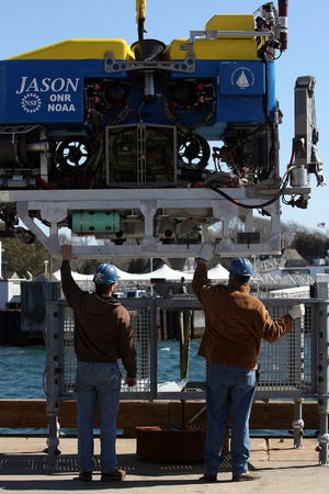 The Jason is moved into position for tests off the docks at Woods Hole Oceanographic Institution by pilot/mechanic Ben Tradd, left, and chief pilot and expedition leader Alberto "Tito" Collasius Jr. Steve Haines/Cape Cod Times