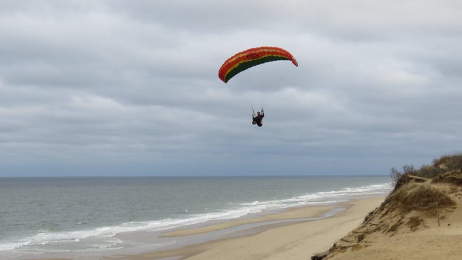 A paraglider set against a cloudy background.