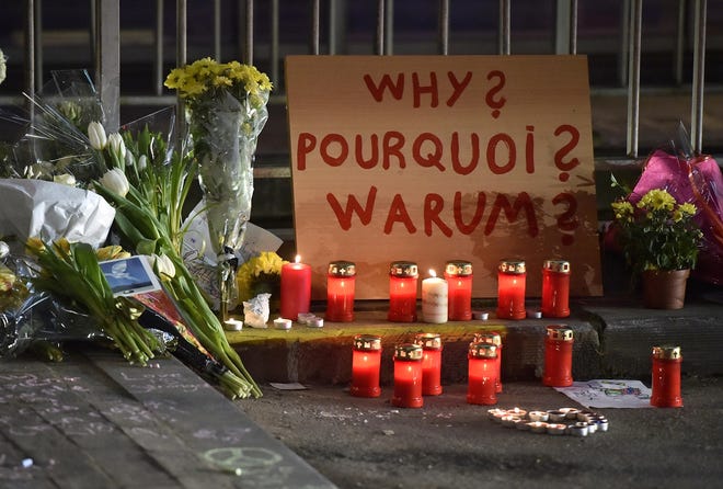 A sign reads "Why?" in English, French and Flemish behind candles and flowers near the Maelbeek metro station, which was attacked Tuesday. The latest on the attacks, A11. AP Photo/Martin Meissner