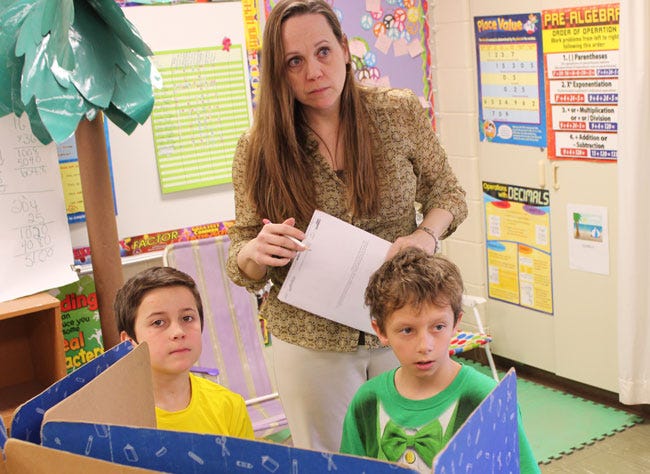 Ruby Mathews, with Riverside Elementary fifth-grade students Dominick Jacobs and Peter Sommers, is one of four full-time substitute teachers hired by Constantine Public Schools. The district said having the four permanent subs available daily minimizes problems when no subs are available to cover a teacher absence.