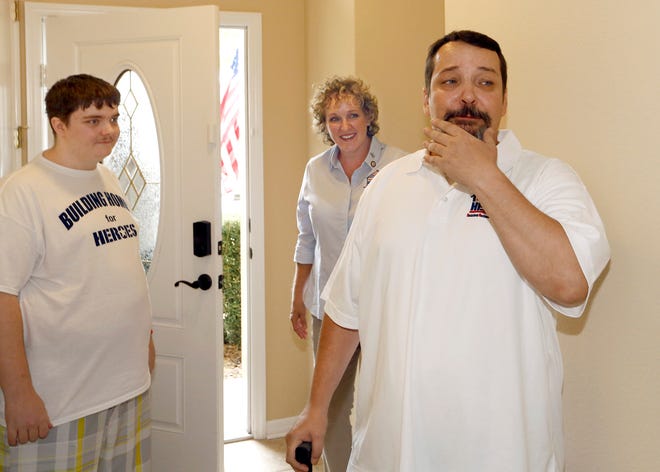 Jonathon Gaspers, left, son of former U.S. Army Sgt. Louis Lund, Kim Valdyke of Building Homes For Heroes, and an emotional Lund enter the home in Davenport.