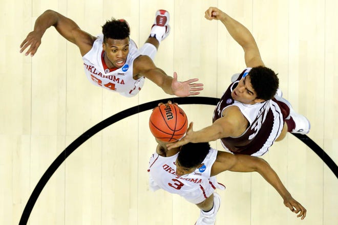 Texas A&M center Tyler Davis, right, pulls a rebound away from Oklahoma guard Christian James, bottom, and Buddy Hield during the first half of an NCAA college basketball game in the regional semifinals of the NCAA Tournament.