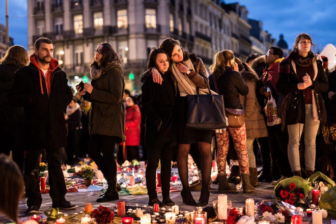 People gather at a memorial site located at the old stock exchange in Brussels on Wednesday, March 23, 2016. Belgian authorities were searching Wednesday for a top suspect in the country's deadliest attacks in decades, as the European Union's capital awoke under guard and with limited public transport after scores were killed or wounded in bombings on the Brussels airport and a subway station. (AP Photo/Valentin Bianchi)