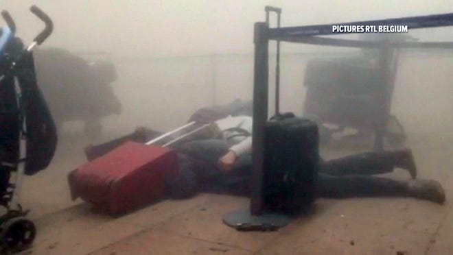 In this still image taken from video from RTL Belgium, unidentified travellers lie on the floor in a smoke-filled terminal at Brussels Airport after explosions Tuesday. AP PHOTO