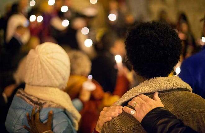 Community members place hands on each others shoulders during a candlelit vigil in support of the "safe harbor" legislation for child victims of human trafficking, Thursday, Dec. 11, 2014, in Atlanta. State Sen. Renee Unterman, of Buford, wants child victims of human trafficking to be immune from prosecution in Georgia, building on the state's 2011 crackdown on prostitution and other sexual crimes. Unterman pre-filed the legislation on Thursday before joining about 50 supporters for a candlelight vigil for victims of sex trafficking at an Atlanta church. SOR ONLN (AP Photo/David Goldman)