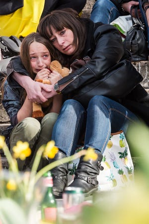 A woman embraces a girl as they observe a memorial site at the Place de la Bourse in Brussels, Saturday, March 26, 2016. Brussels airport officials say flights won't resume before Tuesday as they assess the damage caused by twin explosions in the terminal earlier this week. (AP Photo/Geert Vanden Wijngaert)