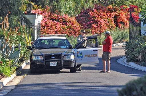 A Goleta Police officer stands guard near a home on Greenhill Way in unincorporated county territory between Santa Barbara and Goleta, Calif.