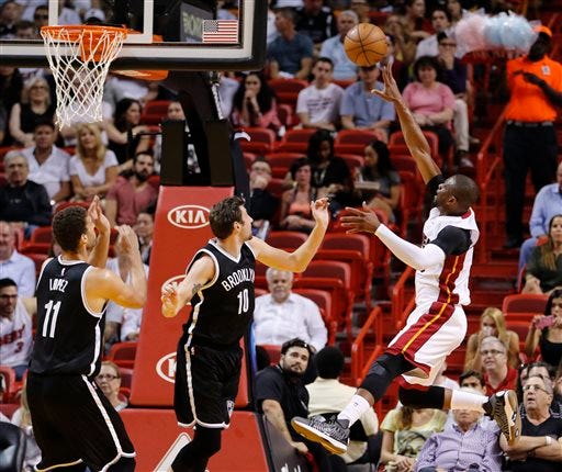 Miami Heat guard Dwyane Wade, right, leaps to score over Brooklyn Nets guard Sergey Karasev (10) and center Brook Lopez (11) in the first quarter of an NBA basketball game, Monday, March 28, 2016, in Miami. (AP Photo/Joe Skipper)