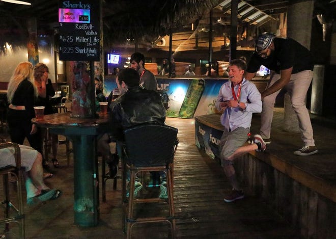 Mathew Troupe helps a restaurant goer back to his seat on March 22 at Sharky's in Panama City Beach, Fla. (Patti Blake | The News Herald)