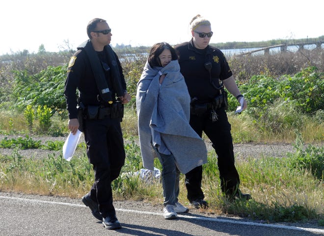San Joaquin Sheriff Deputies escort a woman who swam to shore after her boat capsized in Middle River along Bacon Island road 14 miles west of Stockton. CALIXTRO ROMIAS/THE RECORD