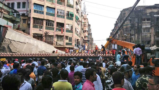 People watch as locals and rescue workers clear the rubbles of a partially collapsed overpass in Kolkata, Thursday, March 31, 2016. At least dozens have been injured and few were killed when a portion of an overpass under construction collapses in a congested area in the eastern Indian city of Kolkata. (AP Photo/Bikas Das)