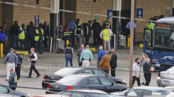 Police and rescue officials with bus patrons outside the Greyhound Bus Station on Thursday in Richmond, Va., on Thursday. One person was killed and three were injured in a shooting at the station.