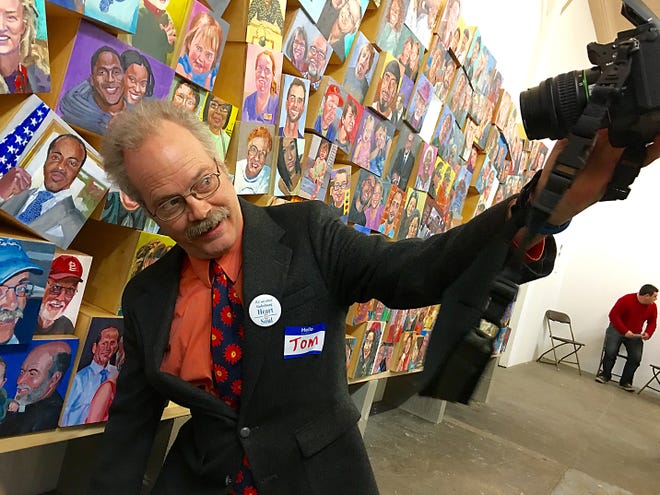 Tom Foley takes a selfie next to the hand-painted portraits during the unveiling of the Galesburg Portrait Project on Thursday evening at The Box in Galesburg. STEVE DAVIS/The Register-Mail