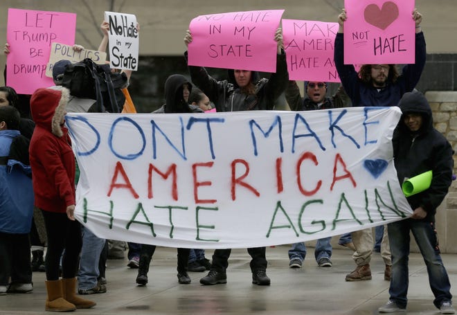 Protesters hold signs on the street in Appleton, Wis., Wednesday, March 30, 2016, where Republican presidential candidate Donald Trump is scheduled to appear for a rally. (AP Photo/Nam Y. Huh)