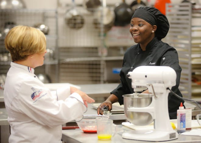 Chef Billie DeNunzio helps student Karissa Kincaid prepare a dish Thursday, March 31, 2016 at the Eastside High School Culinary Institute of Culinary Arts where students competed in a dessert contest judged by local experts with a $500 scholarship and the chance to showcase the winning dessert.