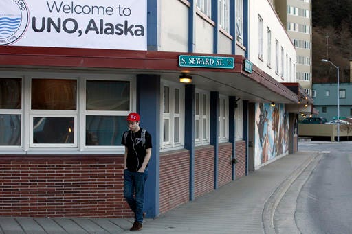 Oliver Coleman passes underneath a sign welcoming people to UNO, Alaska during his walk to work on Friday, April 1, 2016, in Juneau, Alaska. The capital city of Alaska is going by a new name for April Fool's Day - Uno. It's a play on words for the city name of Juneau and part of a promotion with game and toy-maker Mattel Inc., which is drawing attention to new wild cards in its UNO card game. (AP Photo/Rashah McChesney)