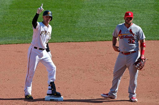 Pittsburgh Pirates' Jordy Mercer (10) stands on second base next to St. Louis Cardinals' Matt Adams (32) after driving in a run with a double off St. Louis Cardinals relief pitcher Seth Maness (43) during the eighth inning of the opening day baseball game in Pittsburgh, Sunday, April 3, 2016. The Pirates won 4-1.