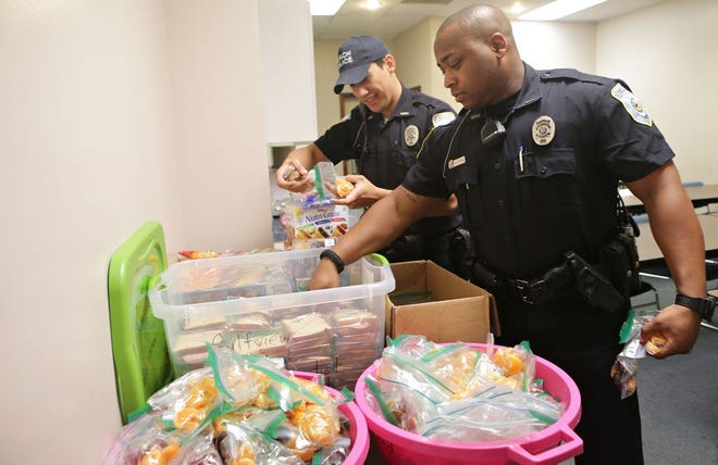 Panama City Beach Police Officers Jonah Pokipala, left, and Erin Williams grab bagged lunches provided by Gulfview Methodist Church on Friday in Panama City Beach.