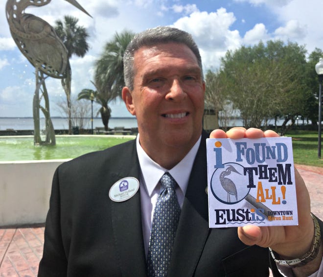 Eustis Mayor Michael Holland holds up one of the "I Found Them All!" badges that people can win for successfully completing The Heron Hunt.