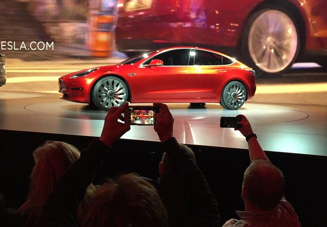 Tesla Motors unveils the new lower-priced Model 3 sedan at the Tesla Motors design studio in Hawthorne, Calif., Thursday, March 31, 2016. It doesn't go on sale until late 2017, but in the first 24 hours that order banks were open, Tesla said it had more than 115,000 reservations. Long lines at Tesla stores, reminiscent of the crowds at Apple stores for early models of the iPhone, were reported from Hong Kong to Austin, Texas, to Washington, D.C. Buyers put down a $1,000 deposit to reserve the car. (AP Photo/Justin Pritchard)