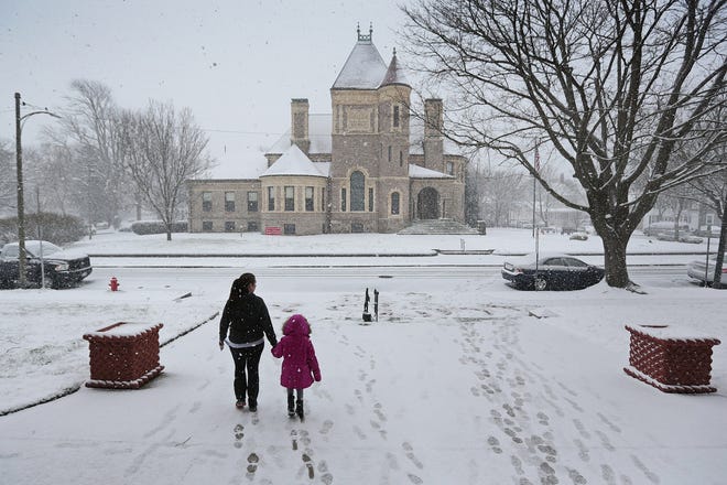 A woman and a young girl walk out of Fairhaven town hall on Monday as a weather front leaves a cover of snow across the region.  PETER PEREIRA/THE STANDARD-TIMES/SCMG