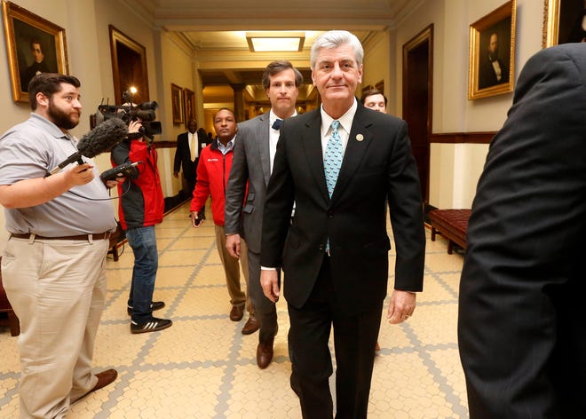 Republican Gov. Phil Bryant, right, walks past reporters on his way to a meeting of a youth jobs program board, at the Capitol in Jackson, Miss., Friday, April 1, 2016. Reporters asked him if he would sign a bill that would let government employees and private businesses cite religious beliefs to deny services to same-sex couples who want to marry. Bryant would not say whether he will sign House Bill 1523, noting he had not received it yet and would need to study it first. (AP Photo/Rogelio V. Solis)