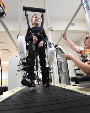 Sara Morgan, a physical therapist with the University of Michigan Health Care System, works Feb. 2 with Braden using the Lokomat, a robotic assistance therapy machine, to help him learn to walk.