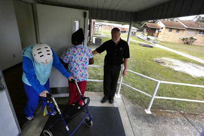 Tacachale's physical plant division director holds the door for a resident and her caregiver at the residential center for the intellectually disabled.