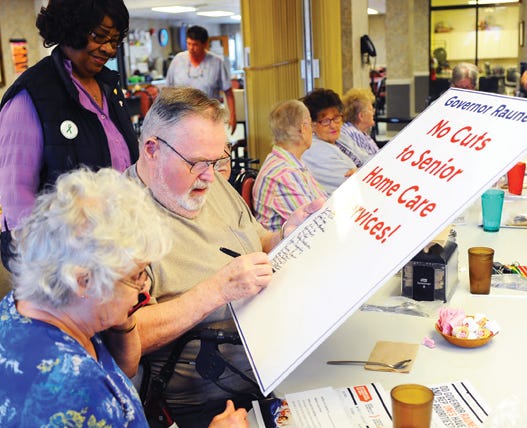 Loren Mutchler adds his name to a list of those demanding opposition to Gov. Bruce Rauner's proposed $200 million in cuts to in-house service programs for seniors. Mutchler was one of many elderly Pekin residents and health care workers who met at the UAW Senior Center in Pekin Wednesday to decry the cuts.
