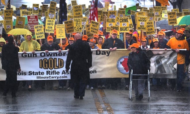 Illinois Gun Owner Lobby Day (IGOLD) participants walk down Capitol Avenue in the pouring rain in Springfield early Wednesday afternoon before they headed inside the Capitol to lobby their individual state legislators. The Illinois State Rifle Association held their annual Illinois Gun Owner Lobby Day in Springfield on Wednesday, April 6, 2016. David Spencer/The State Journal-Register