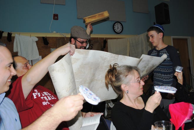 Rabbi Meir Borenstein reads from the Megillah, with help from Eli Weinstein of Goshen, as participants shake noisemakers at the Chabad Of Orange County's Purim event. PHOTO BY STACEY ORZELL