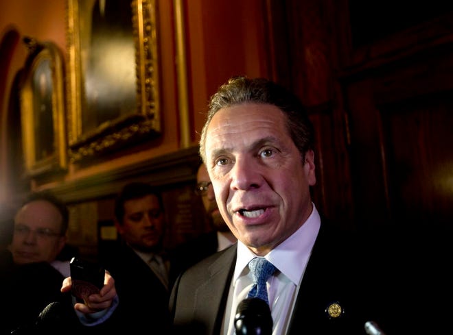 FILE - In this Wednesday, March 30, 2016 file photo, New York Gov. Andrew Cuomo talks to media members outside his office at the state Capitol in Albany, N.Y. New York is set to join California on the path to a $15 minimum wage under an agreement headed to a vote in the state Legislature that would boost the wages of more than 2 million workers. The raise, part of a broader $156 billion state budget deal set for a vote late Thursday or early Friday, contains a series of “calibrated” increases that Cuomo said are designed to help working families while respecting differences in the state’s regional economies. (AP Photo/Mike Groll, File)