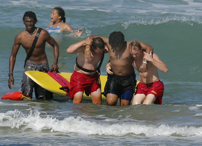 Volusia County lifeguards Ryan Herstein and David Rapoza, right, along with off-duty guard, Gregory Twyford, left, rescue a swimmer after he got caught in the surf and could not make it back to shore Thursday in Daytona Beach. News-Journal/NIGEL COOK