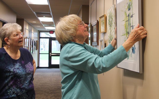 Vivian Schilling, left, and Bev Benne hung artwork in the halls Wednesday at Enrichment Center in Sturgis. They were among those who helped prepare for the center's grand opening, set for Friday.