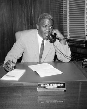 Baseball legend Jackie Robinson speaks on the phone at his desk in the offices of the Chock Full O' Nuts Company on Jan. 7, 1957 in New York. Robinson is the subject of a two-part documentary, "Jackie Robinson" directed by Ken Burns, Sarah Burns and David McMahon airing Monday and Tuesday on PBS. (AP Photo/Jack Harris)