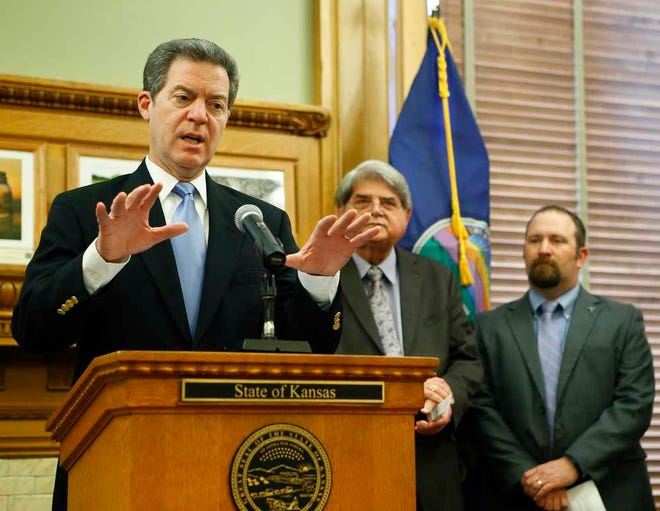 Gov. Sam Brownback, left, alongside Don Gray, the General Manager of the Kansas City Board of Public Utilities, center, and Brice Barton of Tradewind Energy, announces a $613 million wind energy project to be installed in Clark County during a press conference Friday afternoon at the statehouse.