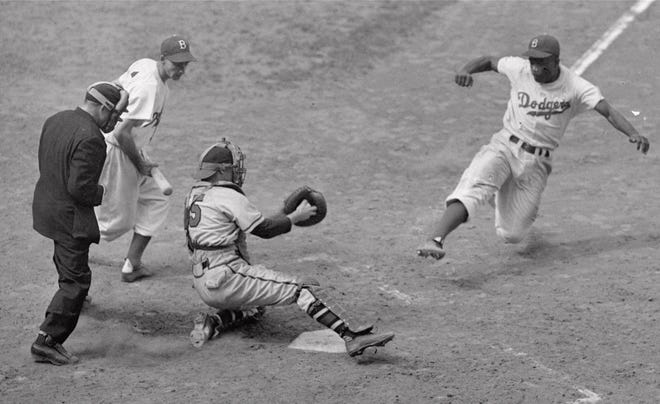 Brooklyn's Jackie Robinson steals home plate as Boston Braves' catcher Bill Salkeld is thrown off-balance on pitcher Bill Voiselle's throw to the plate during a 1948 game at Ebbets Field in New York. Robinson is the subject of a two-part documentary that begins on Monday on PBS.