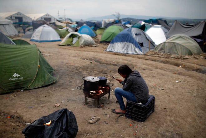 A migrant woman prepares dinner on the fire at the northern Greek border point of Idomeni, Greece, Friday, April 8, 2016. A plan to send back migrants from Greece to Turkey sparked demonstrations by local residents in both countries days before the deal brokered by the European Union is set to be implemented. (AP Photo/Amel Emric)