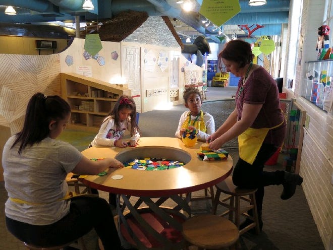 Sunny Moriello Flatts, right, and Ava Flatts, 9, of East Providence, served as family volunteers at the Providence Children's Musem for a year and a half. At left are Natasha Nunez, a Community College of Rhode Island work-study student, and museum visitor Isabella Russo, 6, of Florida.