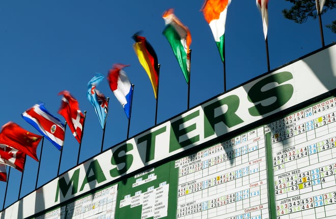 Flags flutter in high winds over a leader board during the third round of the Masters golf tournament Saturday, April 9, 2016, in Augusta, Ga.