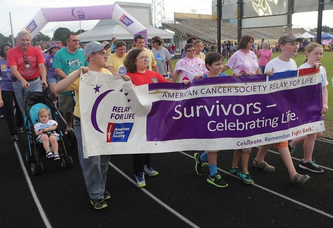 Cancer survivors and caregivers begin the survivor lap kicking off the 2015 Relay For Life fundraiser at Tommy Oliver Stadium.