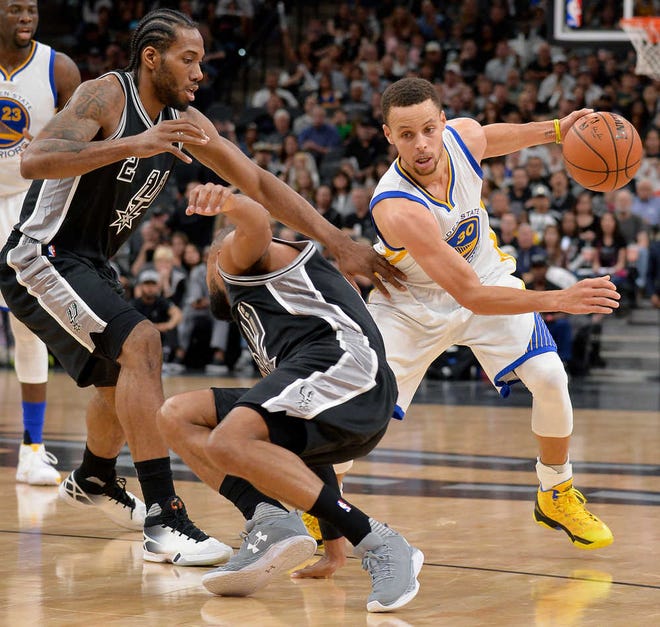 Golden State Warriors guard Stephen Curry drives around San Antonio Spurs' Kawhi Leonard, left, and Patty Mills during the first half on Sunday in San Antonio. (AP Photo/Darren Abate)