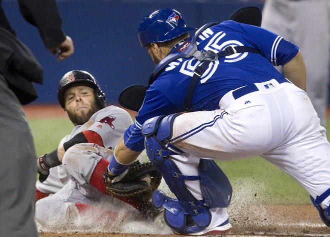 Red Sox's Dustin Pedroia is out at home plate with the tag from Blue Jays catcher Russell Martin during third-inning baseball game action Sunday in Toronto. Fred Thornhill/The Canadian Press via AP